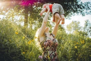 Woman carrying baby near grass