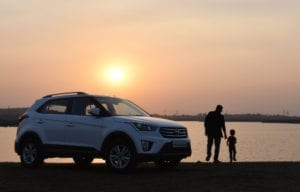 Silhouette of man and child near white hyundai tucson suv during golden hour