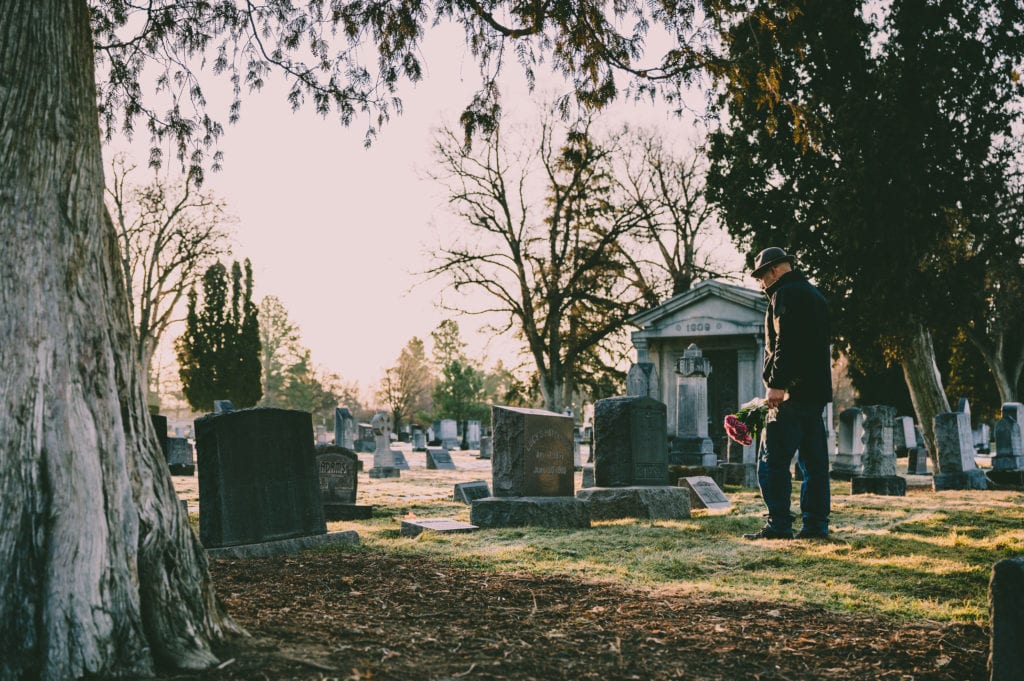 Man in black jacket standing in front of grave