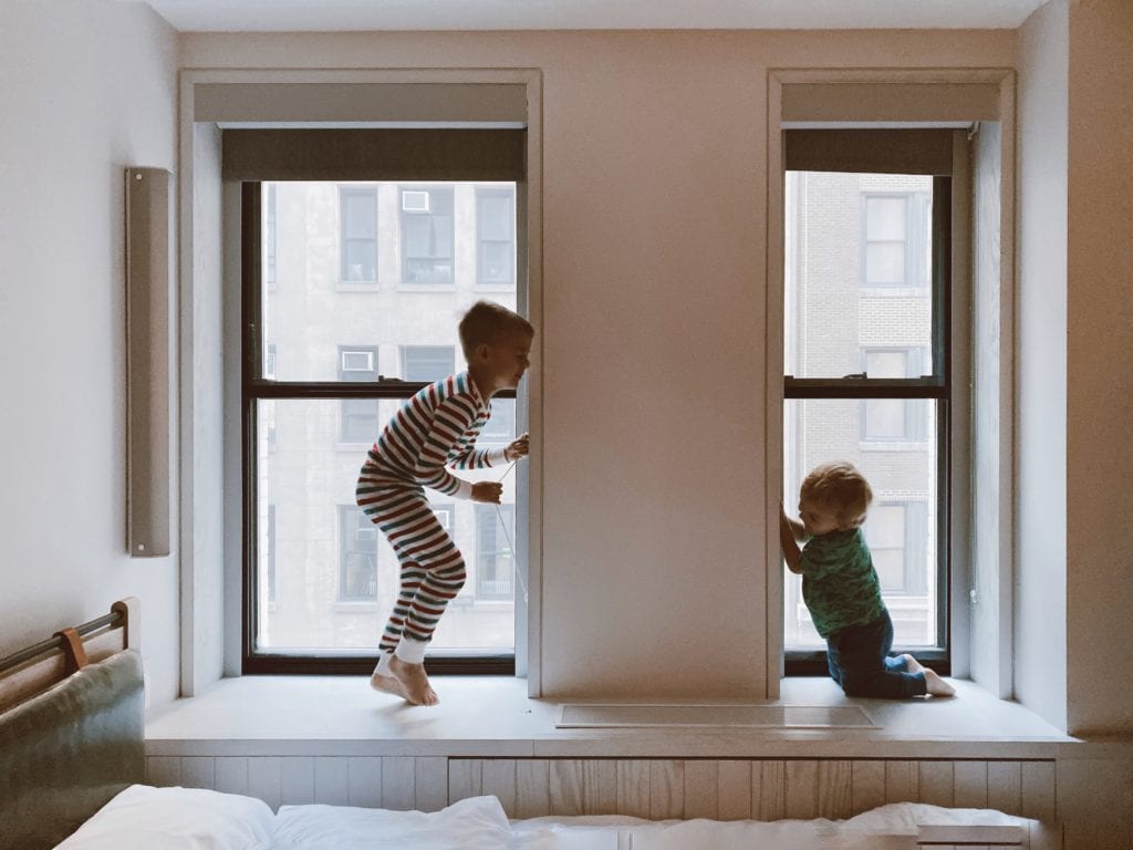 two young kids playing next to a window