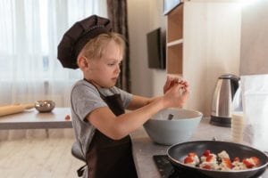 Boy in grey t shirt and black pants sitting on white ceramic bowl