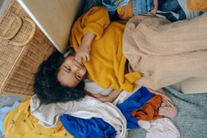 Cute little african american child lying on stack of clothes