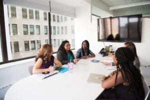 Group of five women gathering inside office