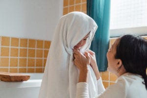 Happy mother rubbing little daughter with big towel