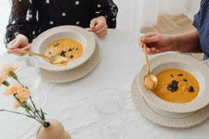 Two female persons eating pumpkin soups