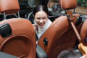 Happy adult asian mother in car together with crop child