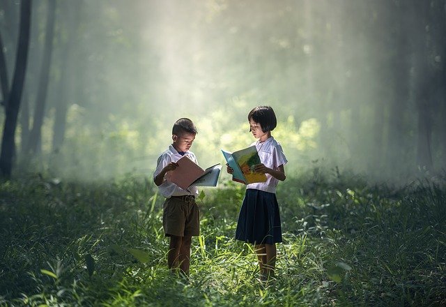 Two children reading books outside.