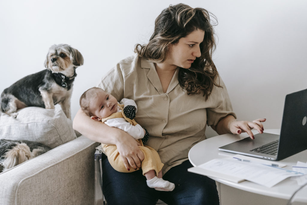 Mother carrying her baby while working from home