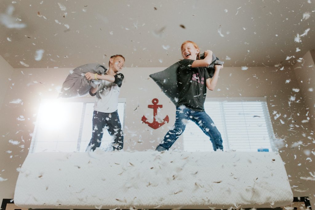 One helpful tip for organizing your kids' shared room is to let them have a pillow fight from time to time, just like these boys in the picture.