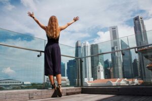 woman raising her hands while standing near glass wall